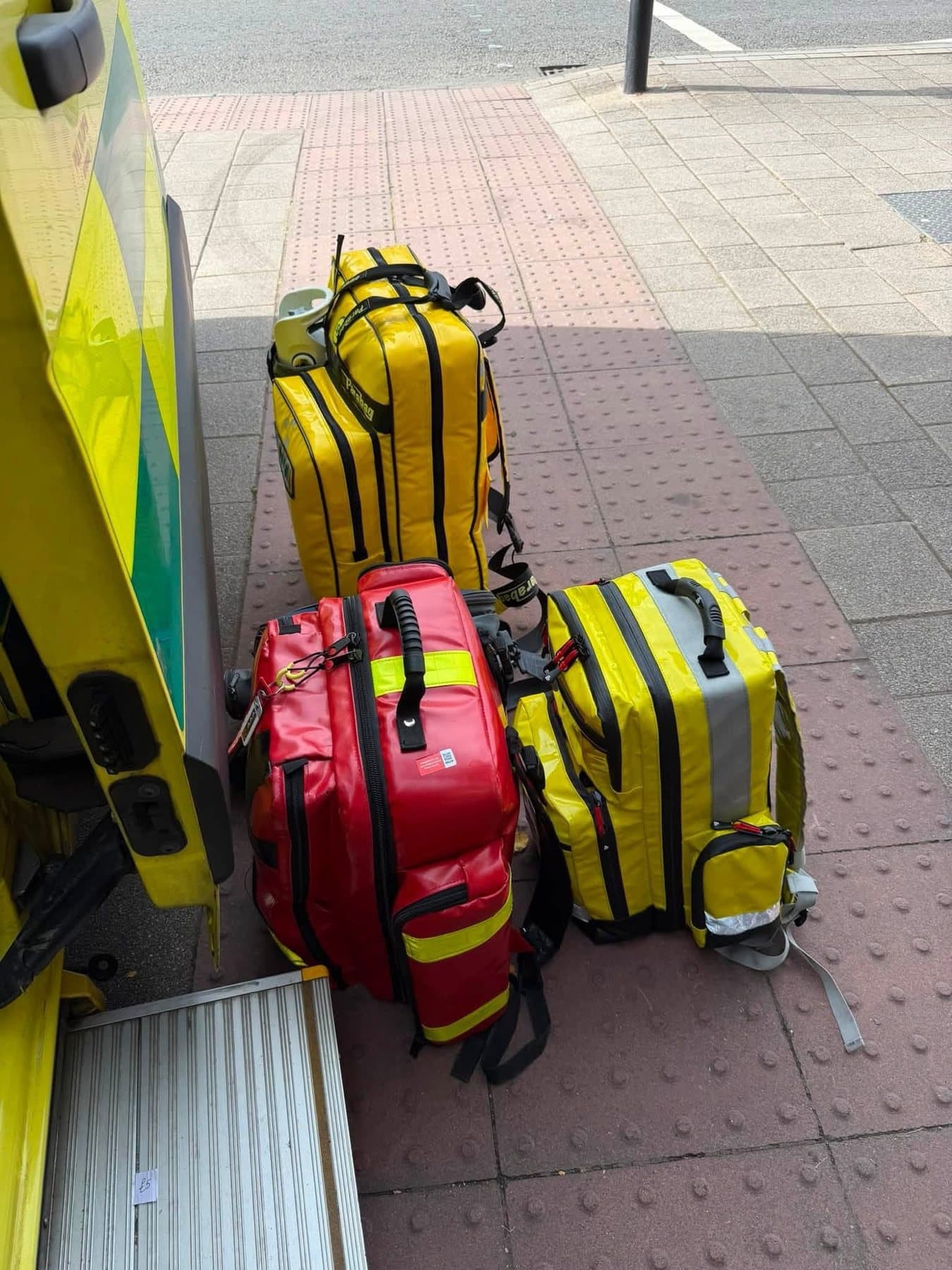 Red and yellow emergency kit bags ready beside an ambulance